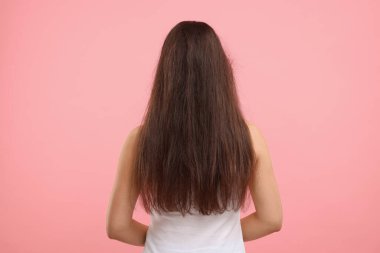 Pembe arka planda tedavi öncesi saçları zarar görmüş bir kadın.