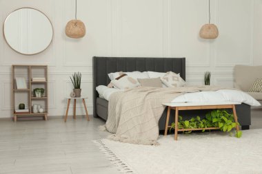 Şık bir yatak odası, geniş rahat bir yatak ve ayna.