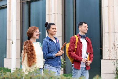 Dışarıda birlikte yürüyen bir grup mutlu genç öğrenci.