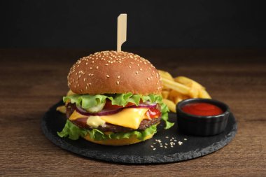 Köfteli leziz burger, domates sosu ve ahşap masada patates kızartması.