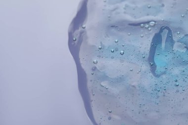 Menekşe arkaplanda şeffaf temizleme jeli, metin için yeri olan üst görünüm. Kozmetik ürünü