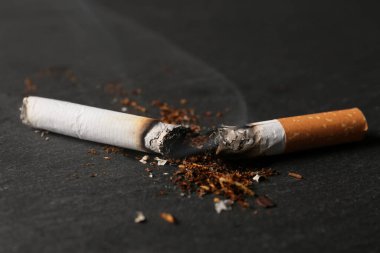 Burnt cigarette, tobacco and smoke on black table, closeup. No smoking concept clipart