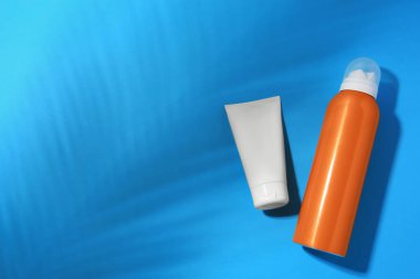 Açık mavi arkaplanda güneş kremleri, düz yatak ve metin için boşluk. Güneş koruma servisi