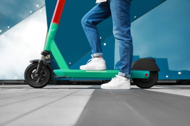 Şehir caddesinde modern elektrikli scooter kullanan kadın, yakın plan.