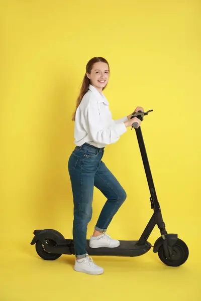 Sarı Arka Planda Modern Elektrikli Scooter Kullanan Mutlu Bir Kadın — Stok fotoğraf