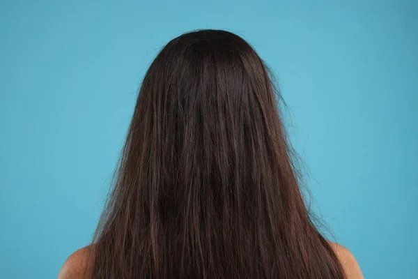 ライトブルーの背景 バックビューで破損した混乱した髪の女性 — ストック写真