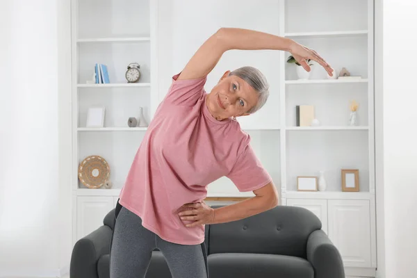 Senior woman in sportswear stretching at home