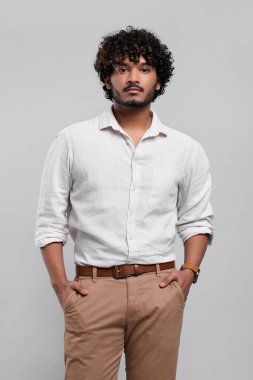 Açık gri arka planda yakışıklı bir genç.