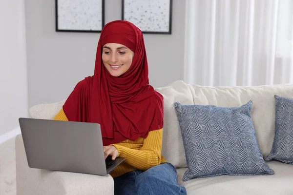 部屋のソファーでノートパソコンを使ったムスリム女性 テキスト用スペース — ストック写真