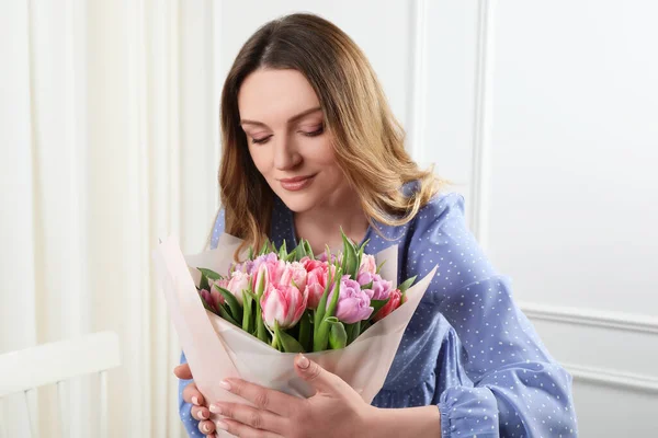 屋内で美しいチューリップの花束を持つ幸せな若い女性 — ストック写真
