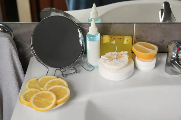 Lemon face cleanser. Fresh citrus fruits, personal care products and mirror on sink in bathroom
