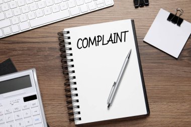 Sözcük şikayetli defter, bilgisayar klavyesi, hesap makinesi ve kırtasiye ahşap masa üzerinde düz konum