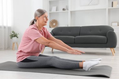 Spor giyim bölümündeki son sınıf kadın evde spor minderinde esniyor.