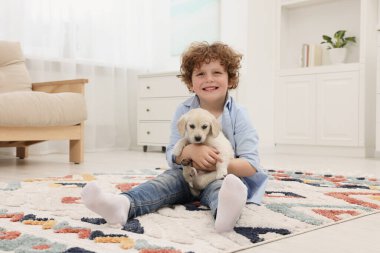 Evdeki halıda sevimli köpek yavrusu olan küçük çocuk.