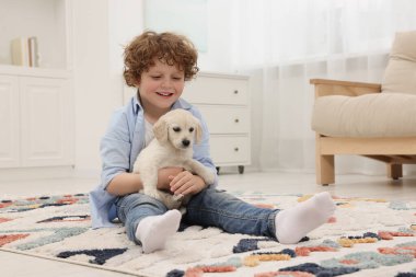 Evdeki halıda sevimli köpek yavrusu olan küçük çocuk.