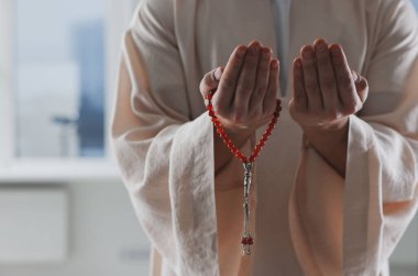 Misbaha 'lı Müslüman bir adam pencerenin yanında dua ediyor, yakın plan. Metin için boşluk