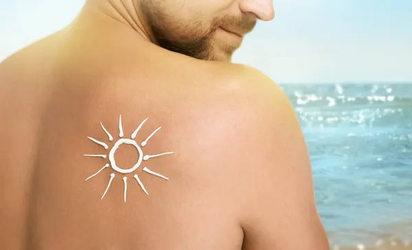 Sun protection. Man with sunblock on his back near sea, closeup