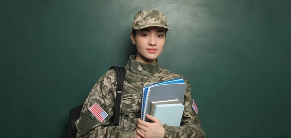 Military education. Cadet with backpack and notebooks near green chalkboard
