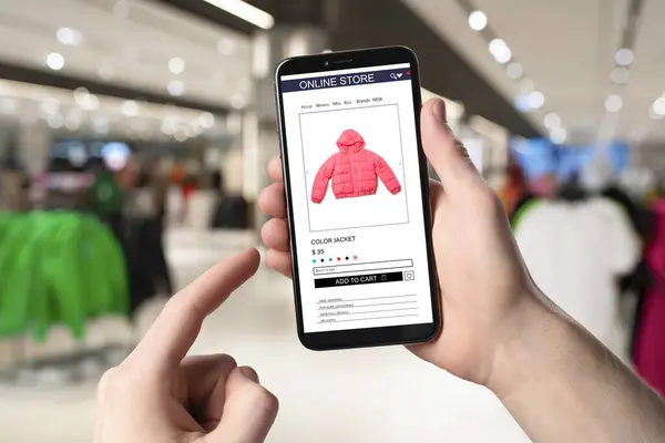 Man visiting shop to take ordered jacket indoors, closeup. Online store website on device screen