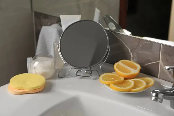 Lemon face wash. Fresh citrus fruits, personal care products and mirror on sink in bathroom