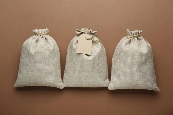 Tied burlap bags on brown background, flat lay