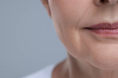 Gri arka planda yaşlı cildi olan yaşlı bir kadın, yakın plan ve mesaj için yer. Yenilenme tedavisi