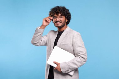 Açık mavi arka planda dizüstü bilgisayarı olan gülümseyen adam. Metin için boşluk