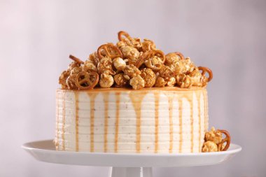 Hafif arka planda patlamış mısır ve simit ile süslenmiş karamel damlalı kek, yakın plan.