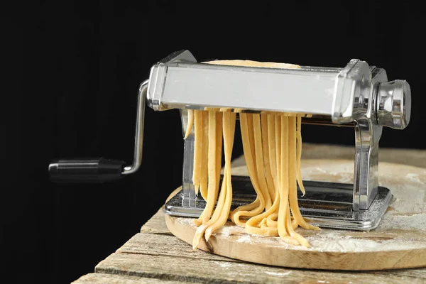 Pasta Maker Met Rauw Deeg Houten Tafel Tegen Zwarte Achtergrond — Stockfoto