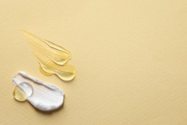 Sarı arka planda şeffaf jel ve beyaz krem örnekleri. Metin için boşluk