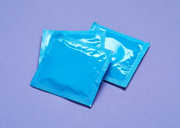 紫色の背景のコンドームパッケージ 安全なセックス — ストック写真