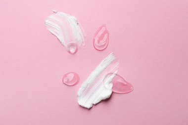 Pembe arka planda kozmetik jel ve krem örnekleri.