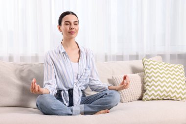 Evdeki kanepede meditasyon yapan bir kadın, mesaj için yer.