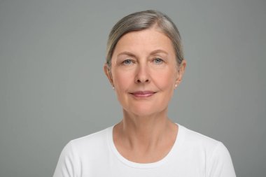 Gri arka planda yaşlanan yaşlı bir kadının portresi. Yenilenme tedavisi