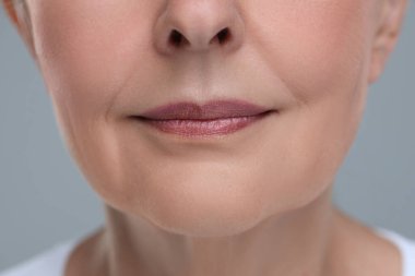 Gri arka planda yaşlanan yaşlı bir kadın, yakın plan. Yenilenme tedavisi