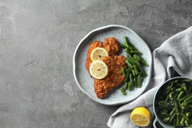 Gri masada limon ve yeşil fasulyeyle servis edilen lezzetli şnitzeller. Metin için boşluk