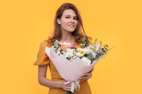 黄色の背景に美しい花の花束を持つ幸せな女性 — ストック写真