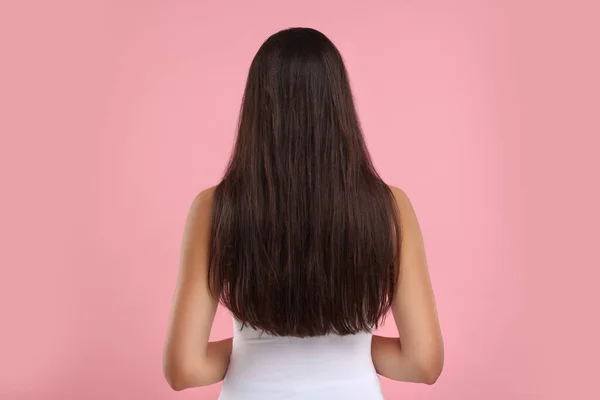 Woman with damaged messy hair on pink background, back view
