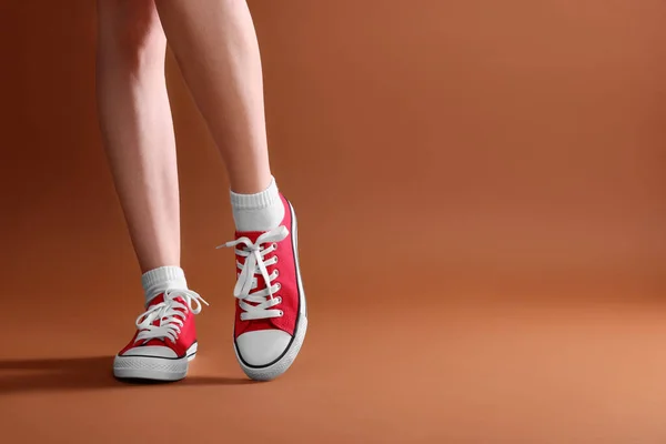 Kahverengi Arka Planda Klasik Kırmızı Spor Ayakkabı Giyen Bir Kadın — Stok fotoğraf