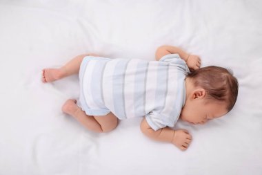 Sevimli yeni doğmuş bebek beyaz yumuşak bir yatakta uyuyor.