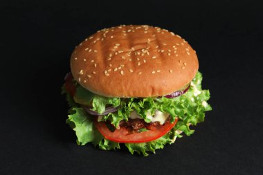 Köfteli leziz burger ve siyah arka planda marul.