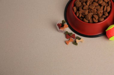 Vitaminler, oyuncak top ve bej arka planda kuru hayvan mamaları. Görüntü üstü. Metin için boşluk