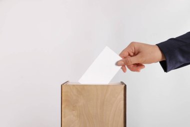 Kadın oyunu açık gri arka planda sandığa koyuyor, yakın plan.