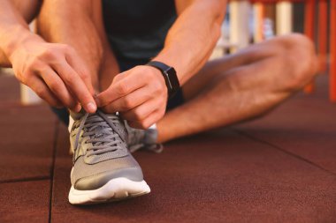 Spor salonunda antrenmandan önce ayakkabı bağcıklarını bağlayan adam, yakın plan.