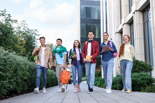 Group of happy students walking together outdoors, low angle view