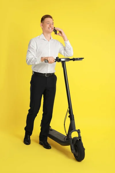 快乐男人用现代电动车在智能手机上用黄色背景说话 — 图库照片