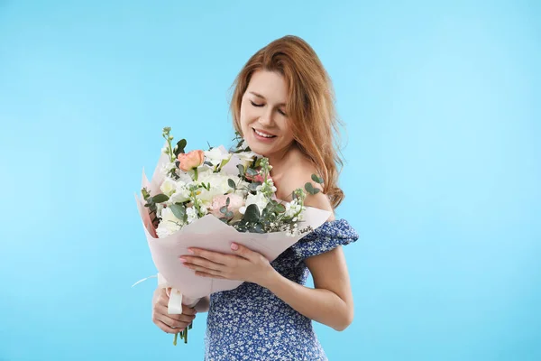 ライトブルーの背景に美しい花の花束を持つ幸せな女性 — ストック写真