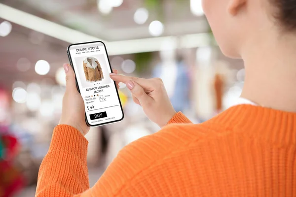 Woman visiting shop to take ordered jacket indoors, closeup. Online store website on device screen