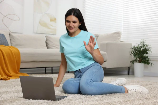 快乐的年轻女人在客厅的地板上通过笔记本电脑进行视频聊天 — 图库照片
