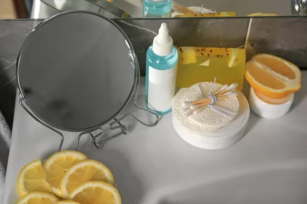 Lemon face cleanser. Fresh citrus fruits, personal care products and mirror on sink in bathroom